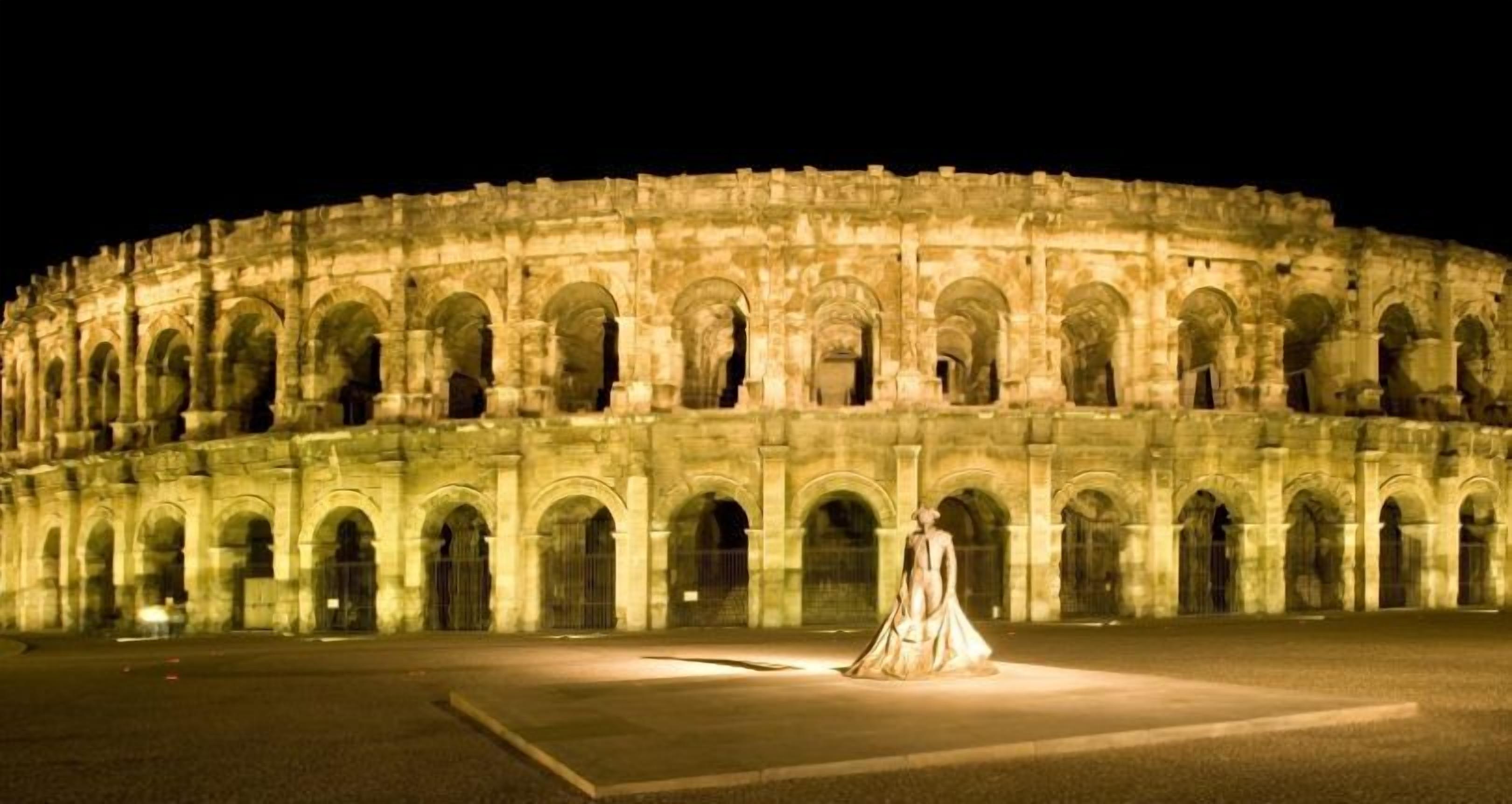 A large, historic amphitheater with multiple levels of arches and a central open space.