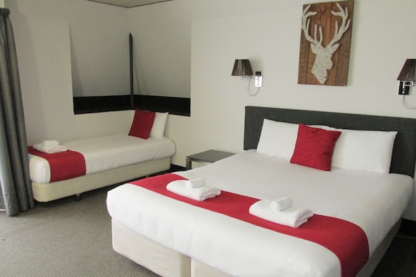 A hotel room with two beds, each with red and white bedding, a nightstand, and a wall-mounted lamp. - 136 On Bealey - Motel (Christchurch)