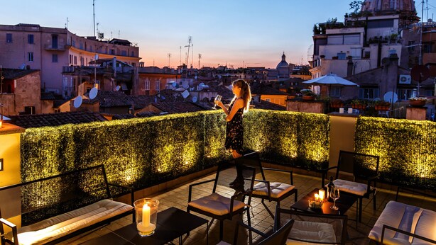 Una terraza en la azotea con asientos, una mesa con velas y vistas a la ciudad al anochecer.