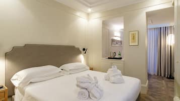 Une chambre d’hôtel avec un grand lit, une table de chevet, un miroir, une commode et une salle de bain visible à travers une porte ouverte.