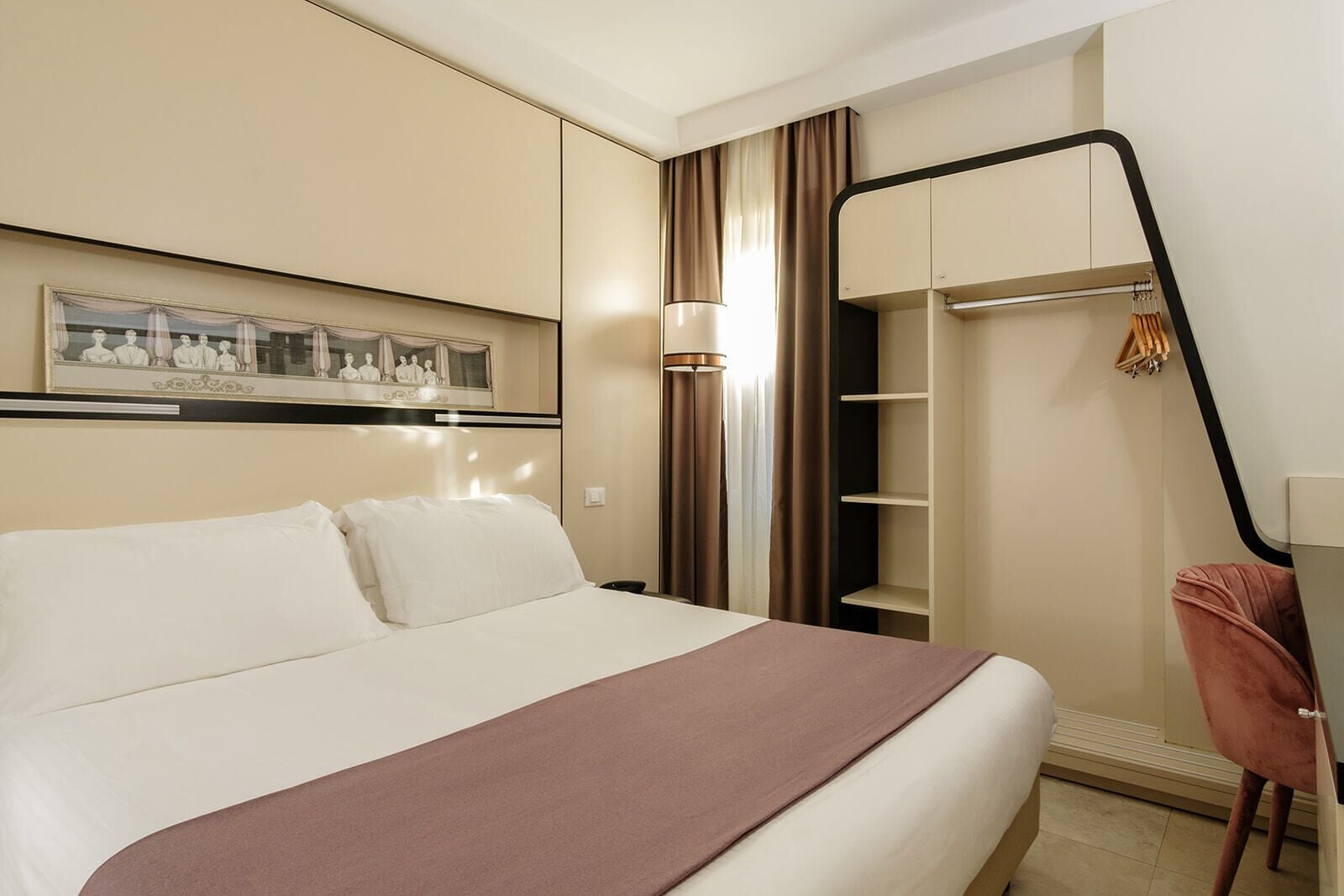 A hotel room with a bed, a wardrobe, a desk, and a chair.