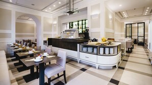 Un comedor moderno con varias mesas y sillas, una barra central con una máquina de café y un piso con estampado de cuadros.
