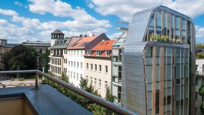 A modern building with a curved glass facade and a balcony with potted plants. - Mikon Eastgate Hotel (Berlin)