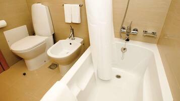 Une salle de bain comprenant des toilettes, un bidet, un lavabo et une baignoire.