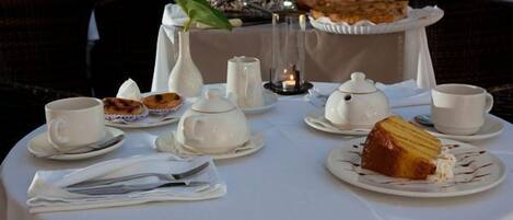 A table set for a meal with white plates, cups, and a teapot.