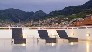 A rooftop terrace with three sun loungers and a table, overlooking a mountainous landscape. - Hotel White Waters (Machico)