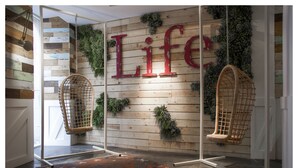 A room with a wooden wall, two wicker chairs, and a 'Life' sign. - Hotel Life Gran Via (Madrid)