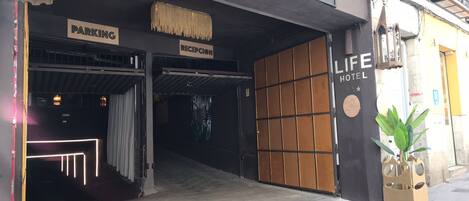 A hotel entrance with a reception area, a parking sign, and a Life Hotel sign.