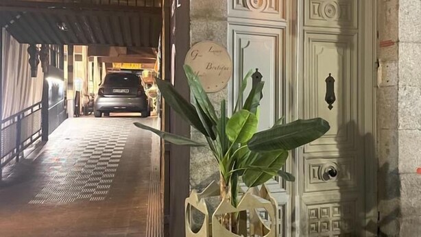 A reception area with a car parked in the background, a potted plant, and a decorative door with a sign. - Hotel Life Gran Via (Madrid)