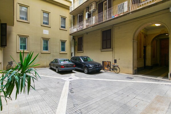A courtyard with two parked cars, a bicycle, and a potted plant.