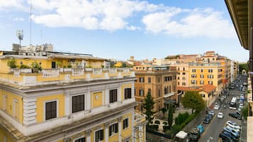 Un hotel con fachada amarilla, varios balcones y vistas a una calle concurrida con coches estacionados.