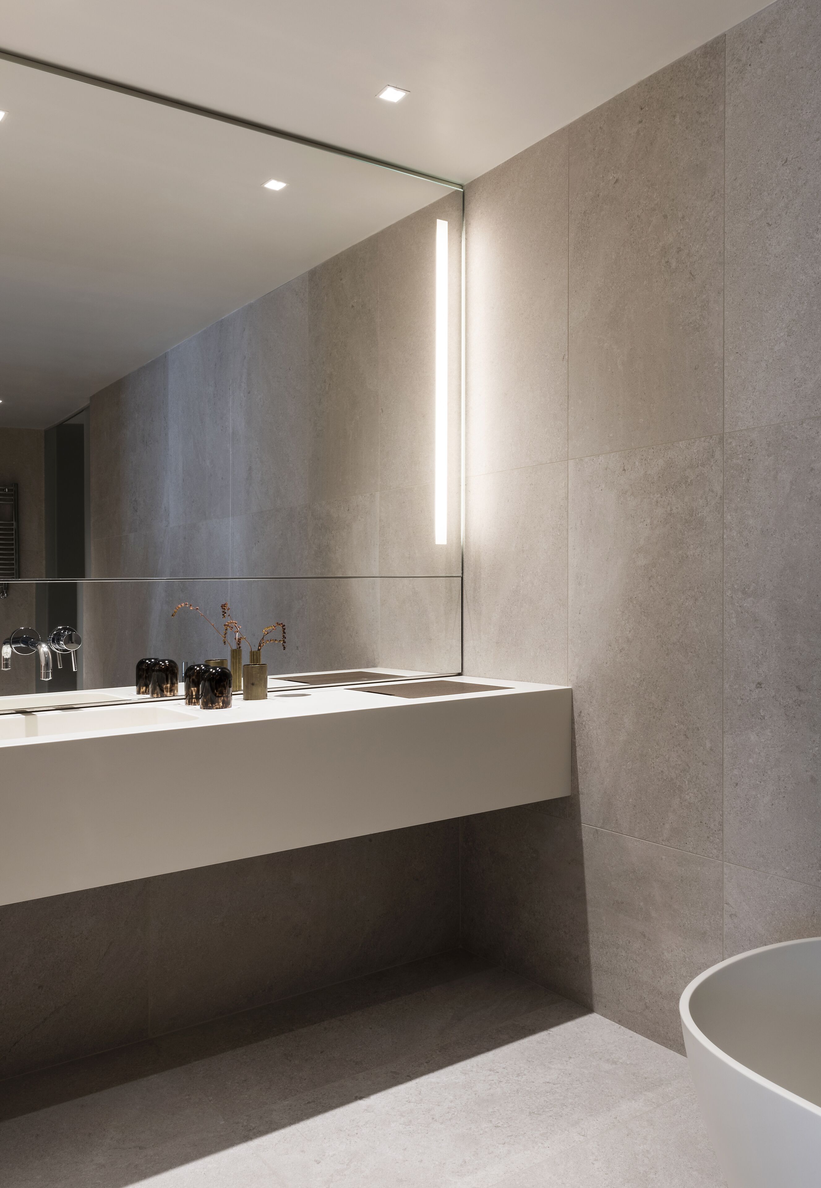 A modern bathroom with a large mirror, a white sink, and a bathtub.
