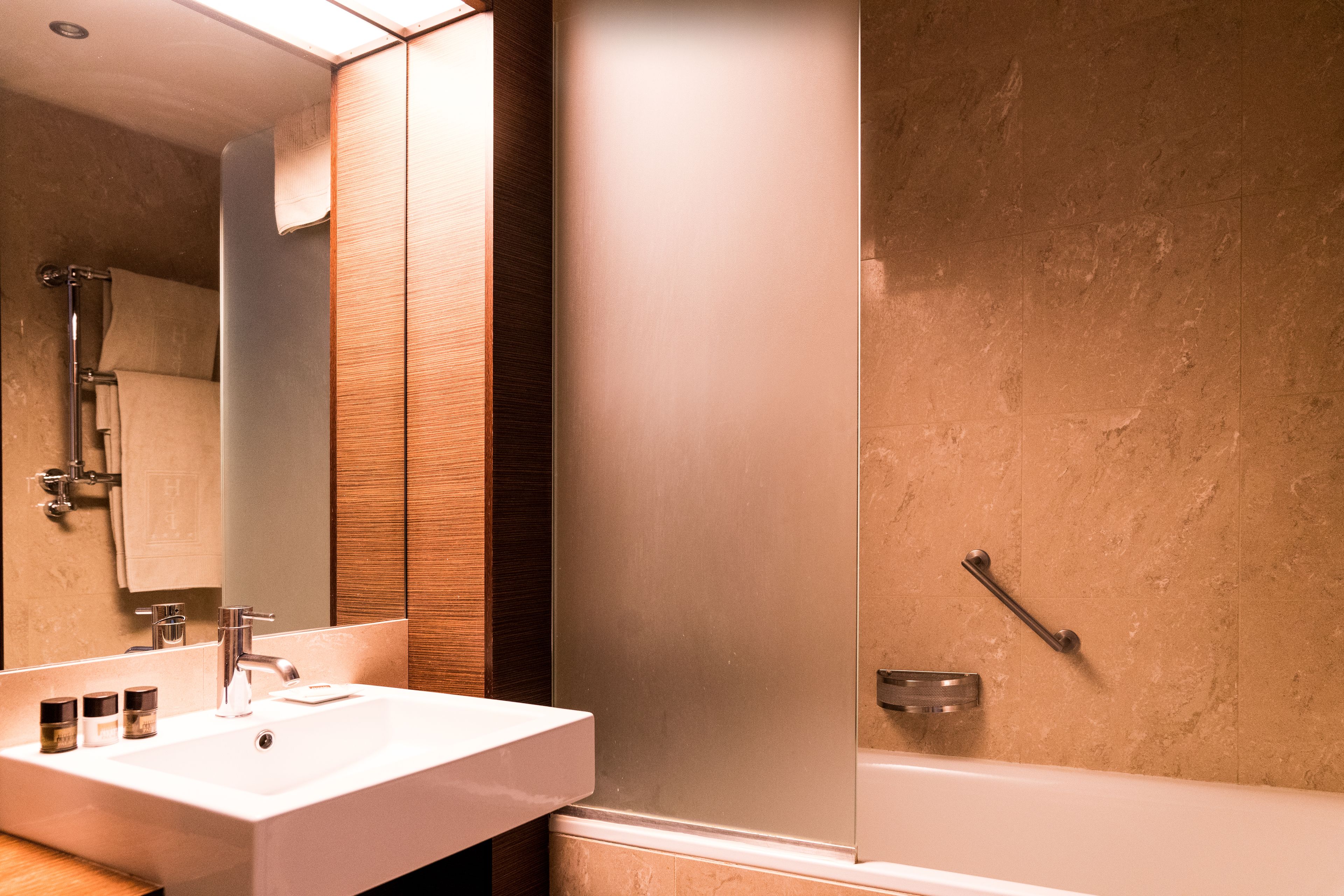 A bathroom with a white sink, mirror, and shower.