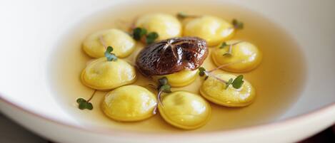 A white bowl with yellow dumplings and a piece of meat, placed on a brown napkin.