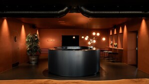 A reception area with a central counter, a potted plant, and a bar area with stools. - Litta Palace Milano Urban Resort (Lainate)