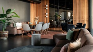 A modern interior with a sofa, chairs, a coffee table, a potted plant, and a wooden accent wall. - Litta Palace Milano Urban Resort (Lainate)