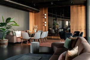 Un interior moderno con un sofá, sillas, una mesa de centro, una planta en maceta y una pared de acento de madera.