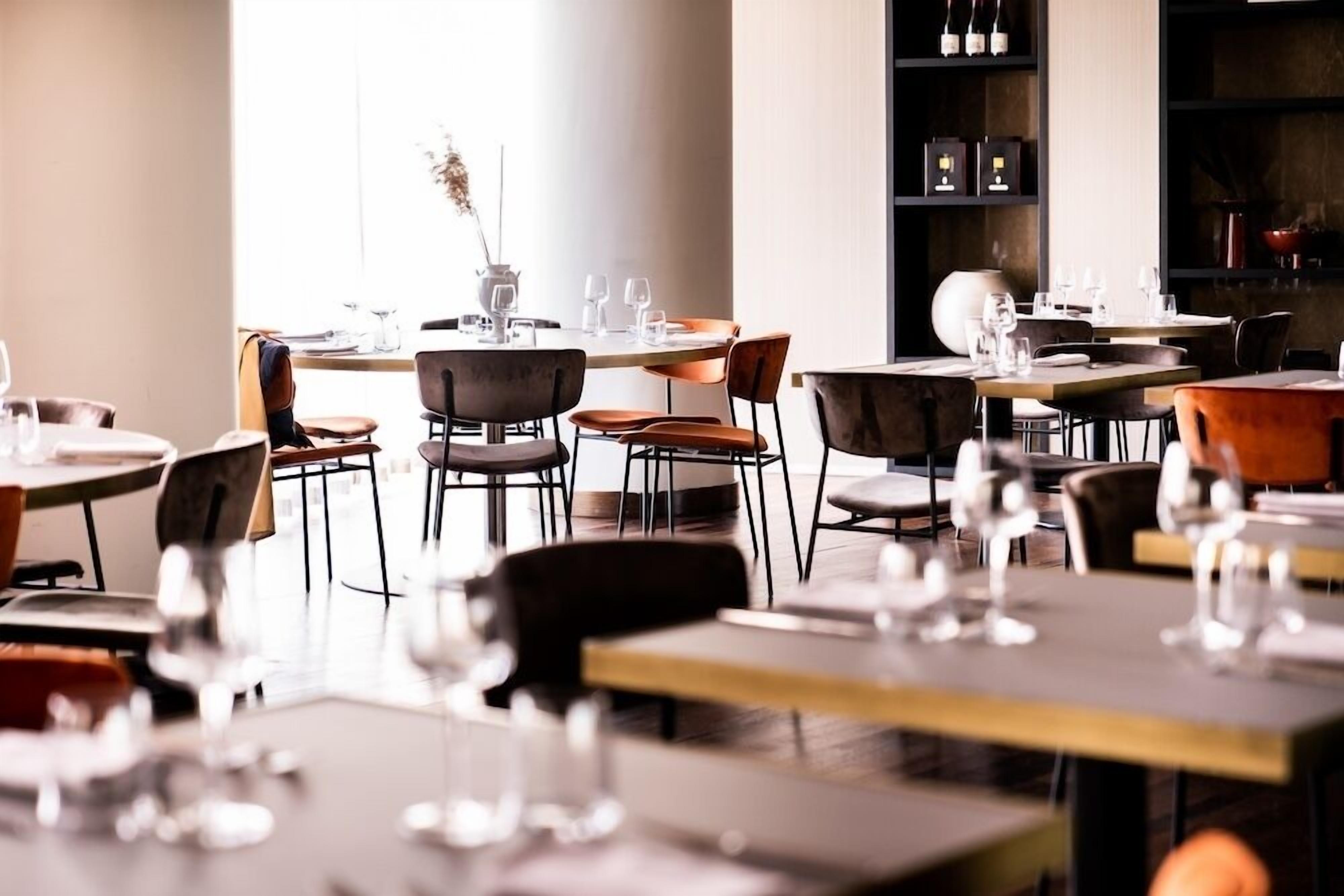 Un restaurante con varias mesas y sillas, algunas con copas de vino y vasos de agua.