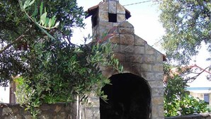 A stone-built outdoor oven with a chimney, surrounded by greenery. - Vis Apartments (Vis)
