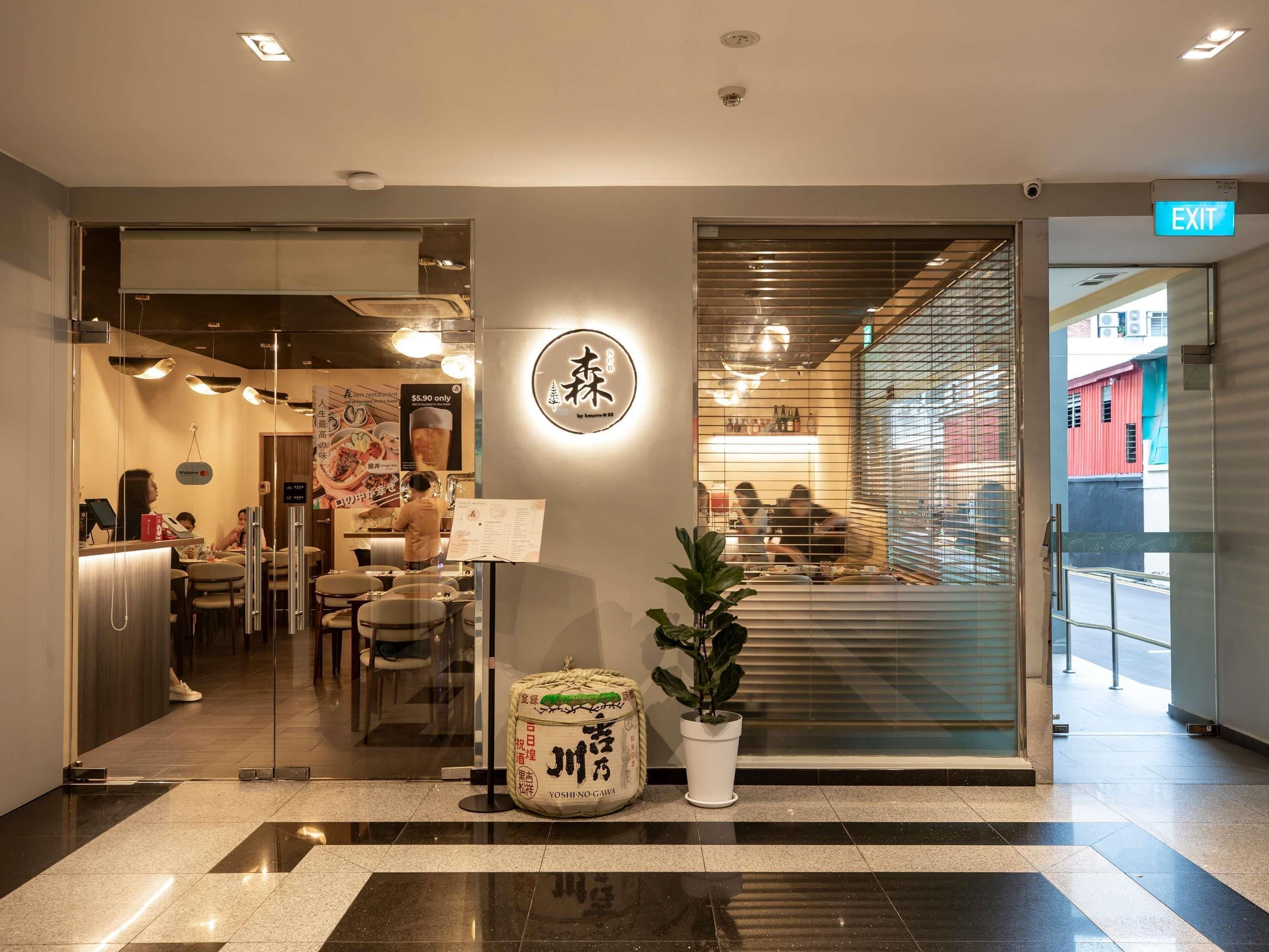 A restaurant interior with a sushi counter, seating area, and an exit sign.