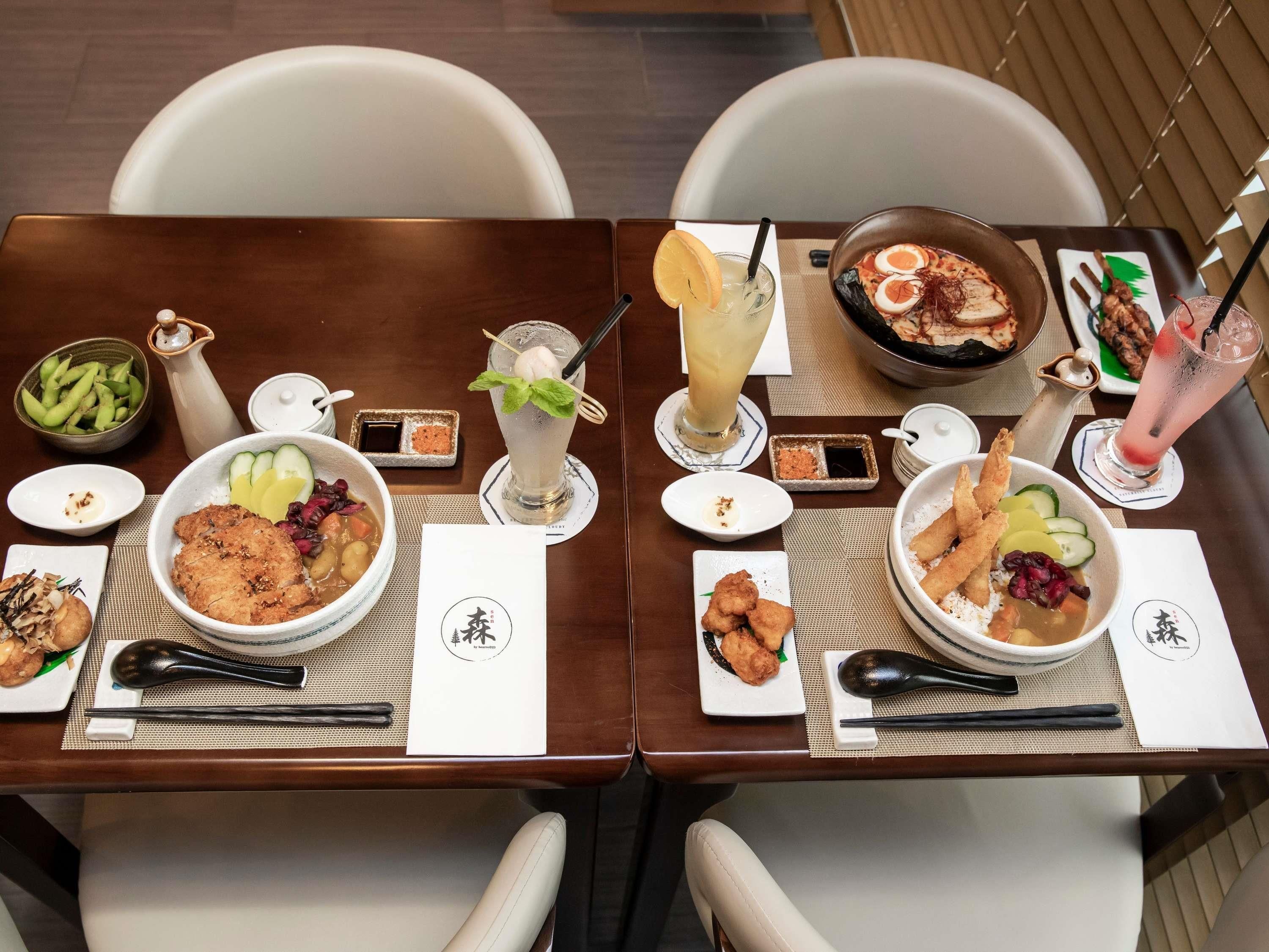 A dining table with various dishes, drinks, and chopsticks.