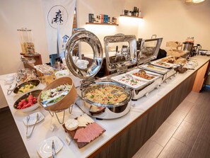 Un bufé con diversas opciones de comida, como ensaladas, carnes y postres.