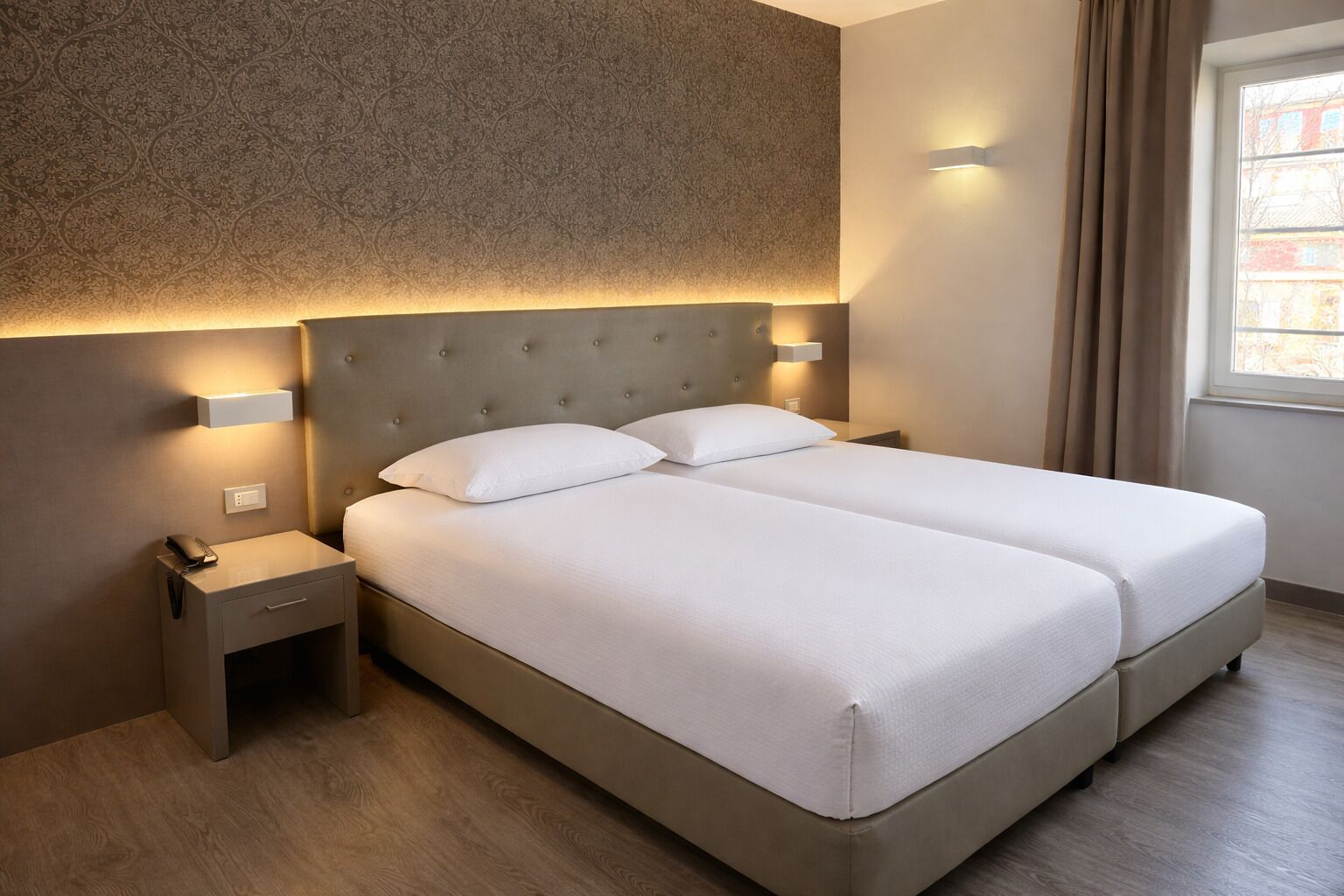 A double bed with a headboard, bedside tables, and wall-mounted lighting.