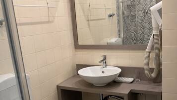 A bathroom with a white toilet, a sink with a mirror above it, and a shower area.