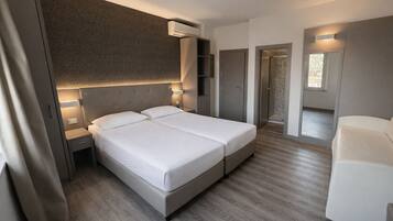 Una habitación de hotel moderna con cama doble, mesitas de noche, armario y zona de estar.