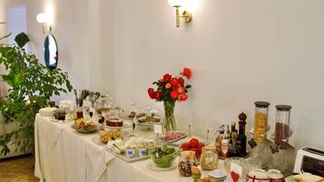 A buffet table with various food items, a vase of red flowers, and a toaster.