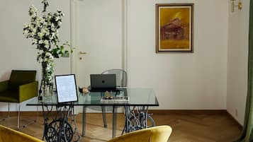 A modern dining area with a glass table, two yellow chairs, a vase of flowers, and a painting on the wall.