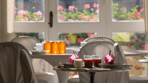 A dining area with a table set for two, featuring a glass of juice, a glass of red juice, and a white mug.