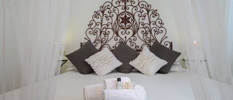 Una cama bien hecha con un cabecero decorativo, almohadas y un juego de toallas.