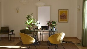 A dining area with two yellow chairs, a glass table, and a vase with flowers.