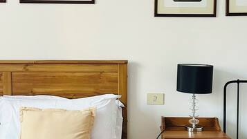 Een hotelkamer met een houten bed, een nachtkastje, een lamp en ingelijste foto’s aan de muur.