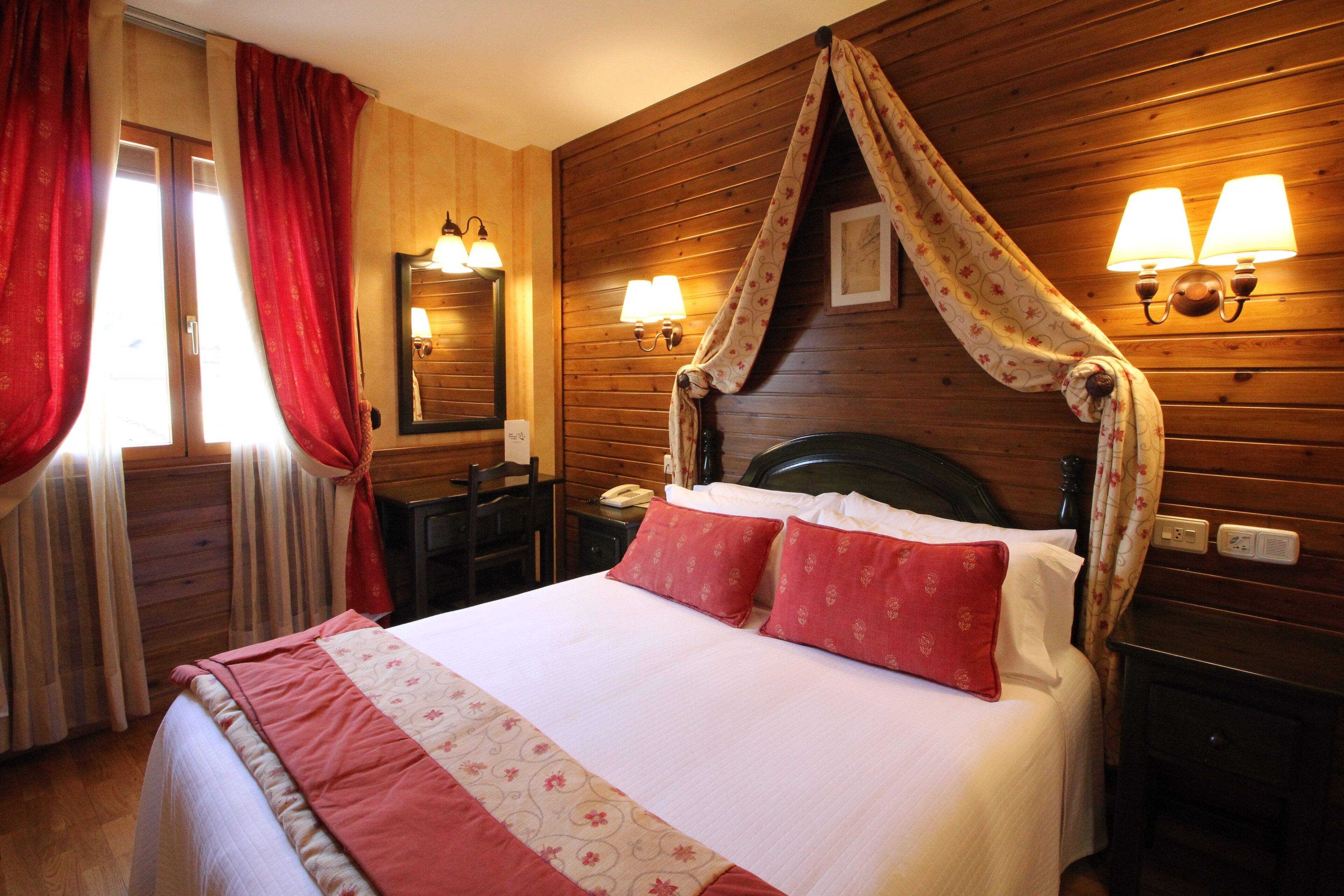 Quarto com painéis de madeira, uma cama, duas luminárias de cabeceira, uma mesa de cabeceira e um espelho.