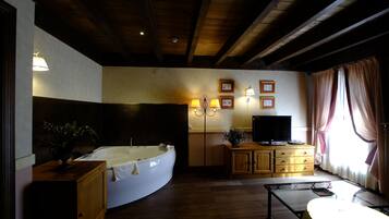 A room with a large bathtub, wooden cabinets, a television, and framed pictures on the wall.