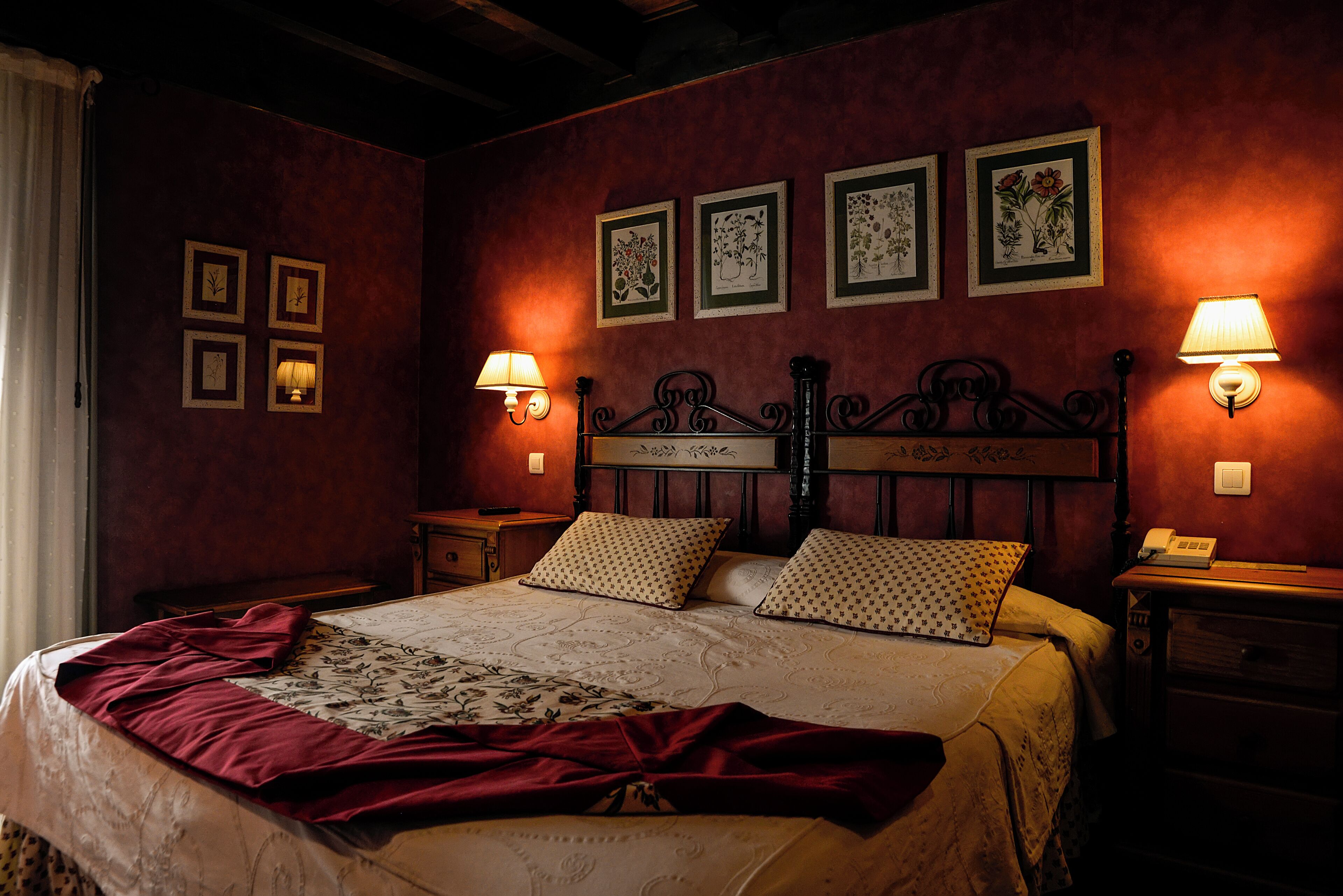A bedroom with a large bed, two bedside tables, a nightstand, and a wall-mounted lamp.