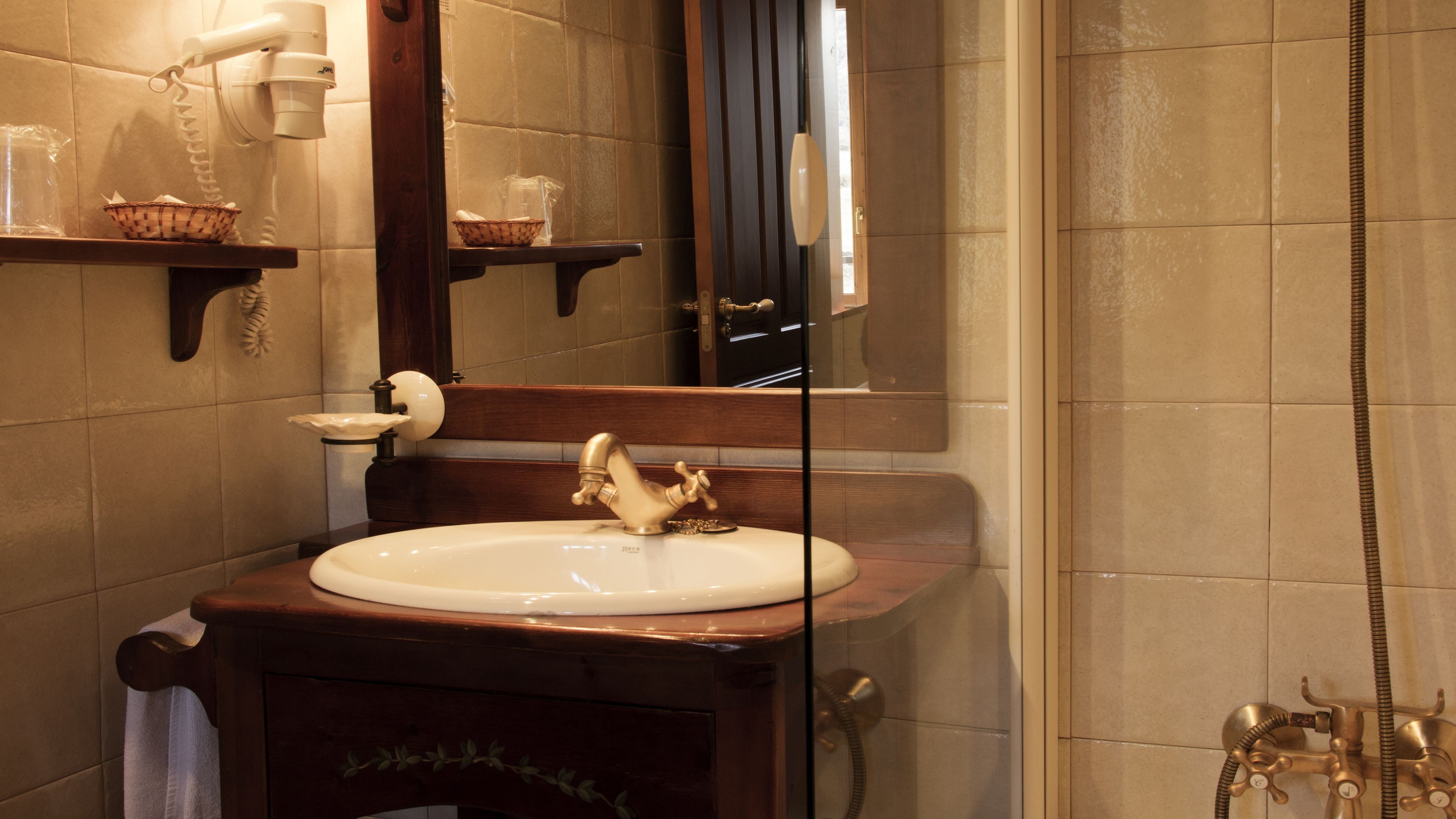 A bathroom with a sink, mirror, and shower.