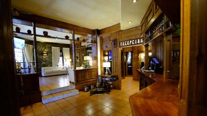 Un hall de hotel con mostrador de recepción, un sofá y una escalera que lleva a otra sala.