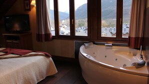 Un dormitorio con una ventana grande, una cama, un televisor y una bañera.