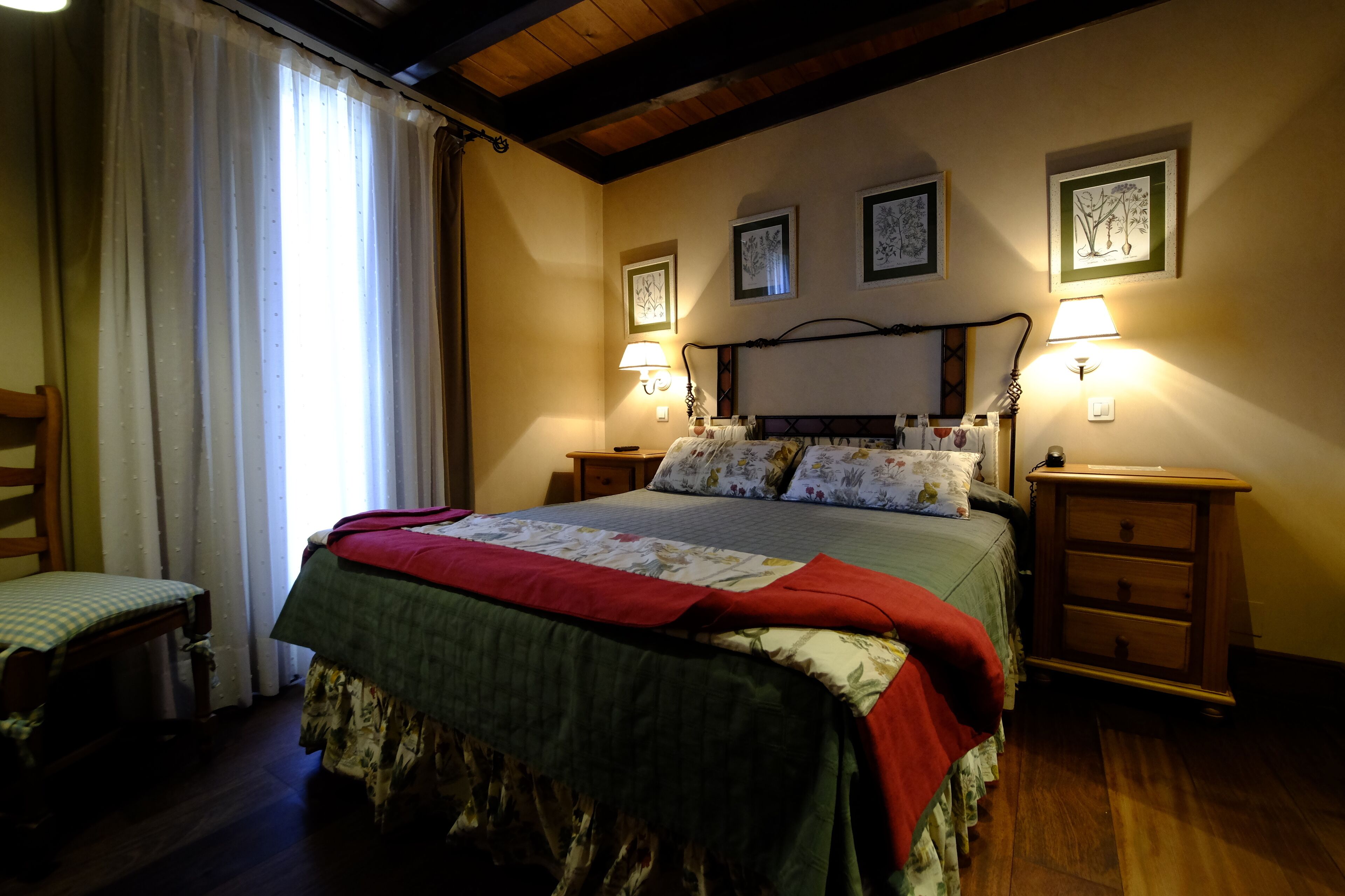A bedroom with a bed, two bedside tables, a chair, and a window with curtains.
