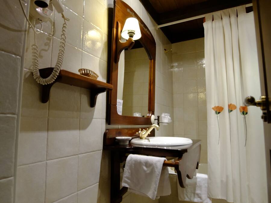 A bathroom with a wooden vanity, a mirror, a sink, a hairdryer, and a shower curtain.
