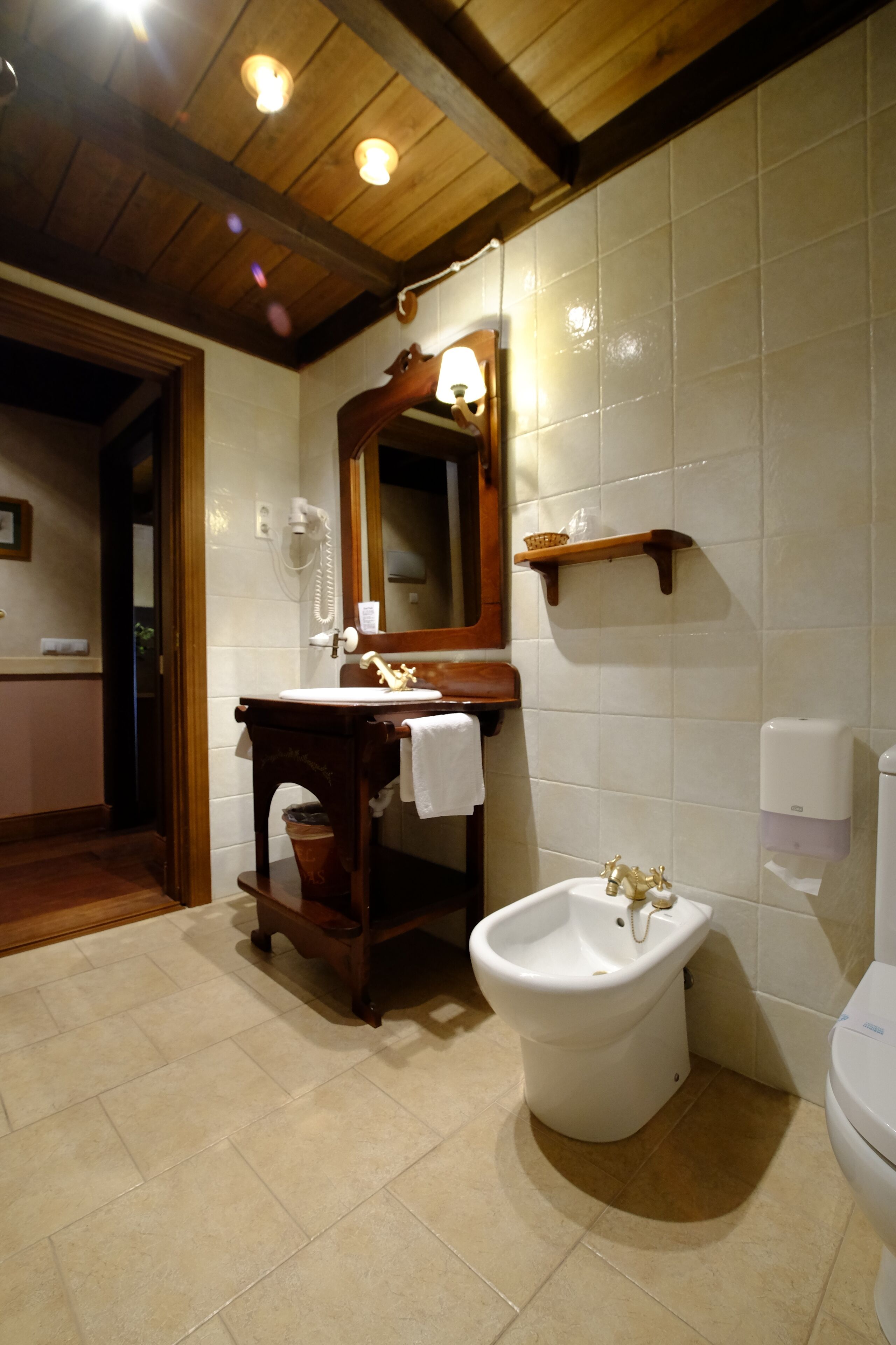 A bathroom with a wooden vanity, a bidet, a toilet, and a mirror.
