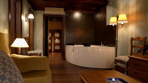 Una habitación con una bañera blanca curvada, una silla de madera, una mesa de madera y una lámpara.