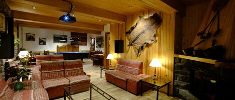 Una sala de estar acogedora con paredes de madera, una chimenea de piedra y un conjunto de sofás.