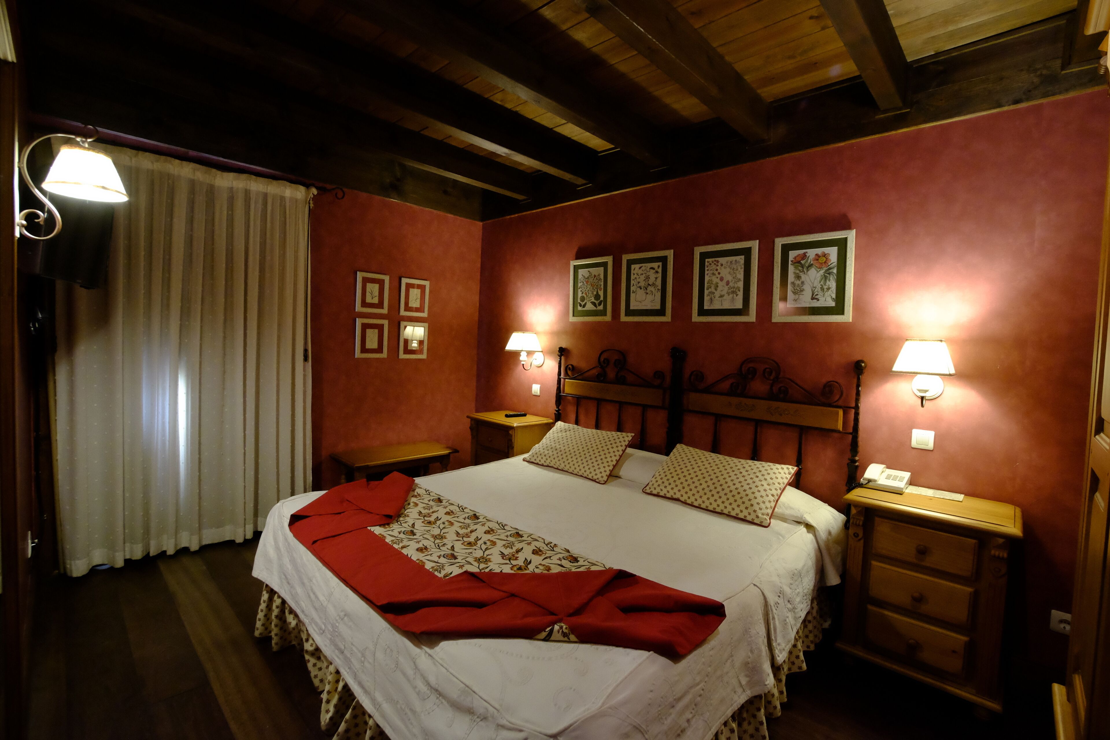 Un dormitorio acogedor con una cama grande, dos mesitas de noche, un cabecero de madera y cuadros enmarcados en la pared.