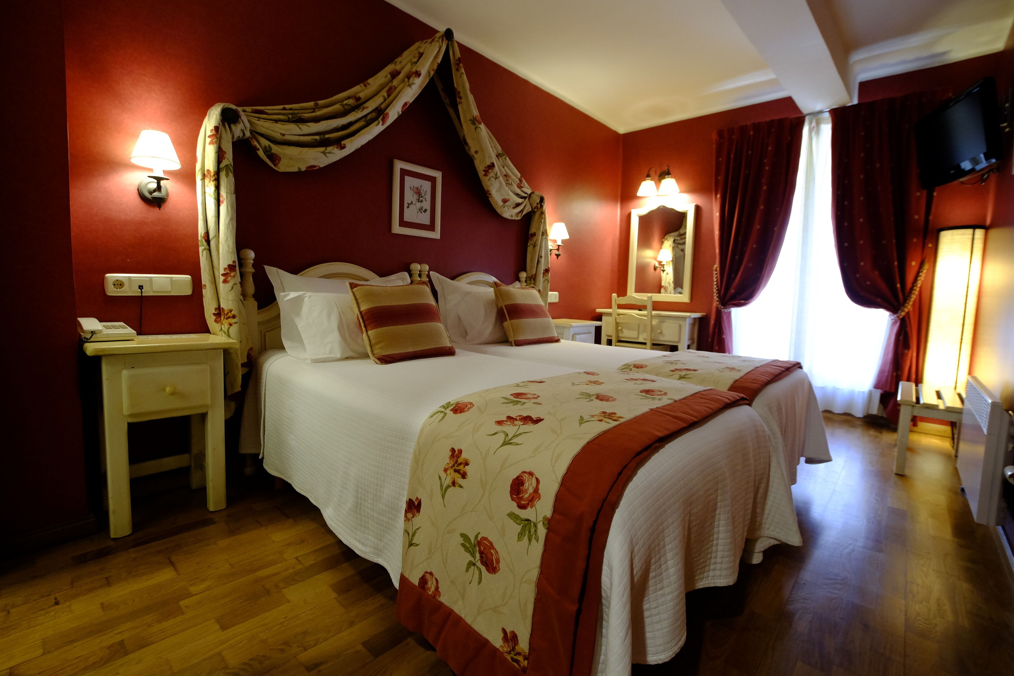 Une chambre à coucher avec un grand lit, deux tables de chevet, une commode, un miroir et un téléviseur.