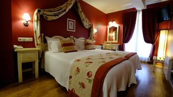 Une chambre à coucher avec un grand lit, deux tables de chevet, une commode, un miroir et un téléviseur.