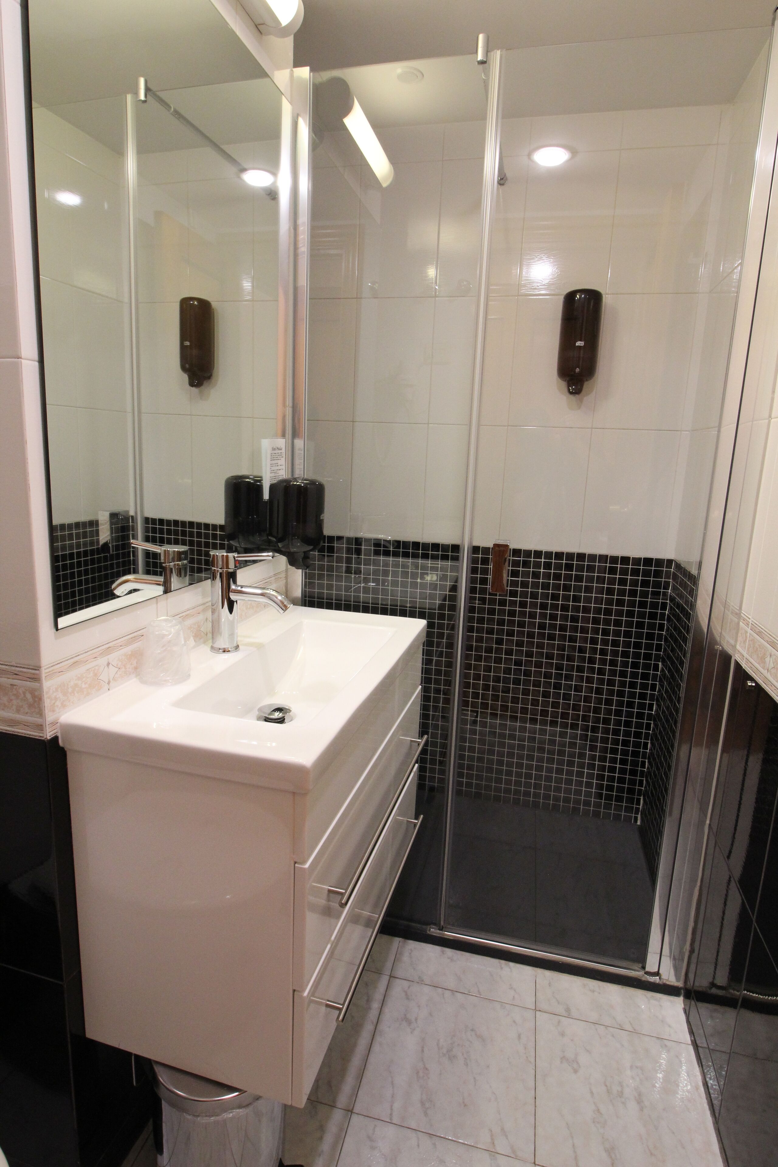 A modern bathroom with a white sink, a glass shower enclosure, and a mirror.